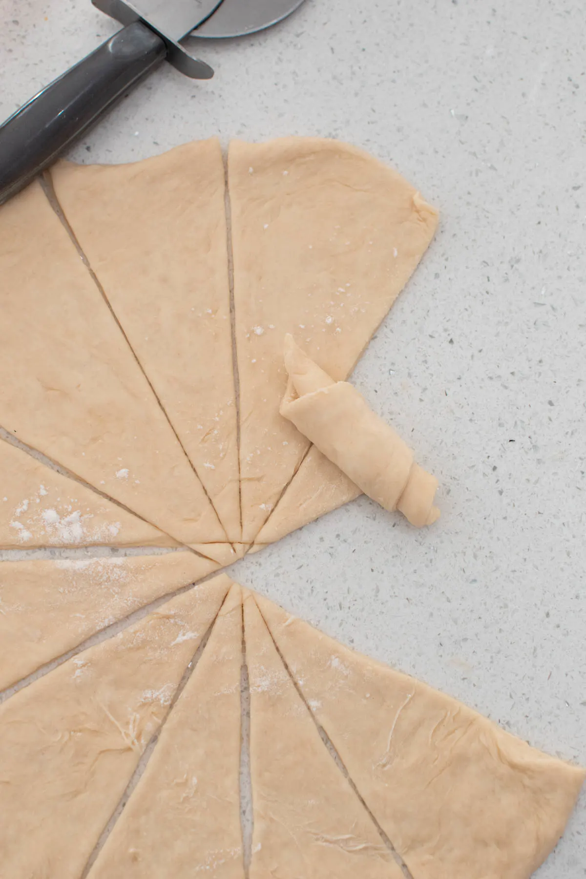 Partially rolled up crescent roll dough next to other triangles of dough.