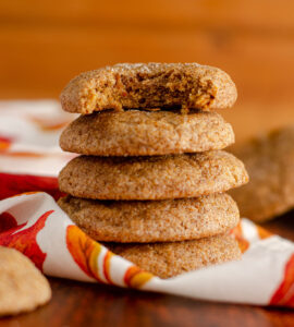 Close up of stack of pumpkin spice cookies with sugar sprinkled on top with decorative kitchen towel.