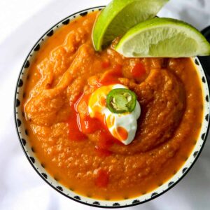 Large bowl of southwestern pumpkin soup with sour cream, hot sauce and jalapenos on top.