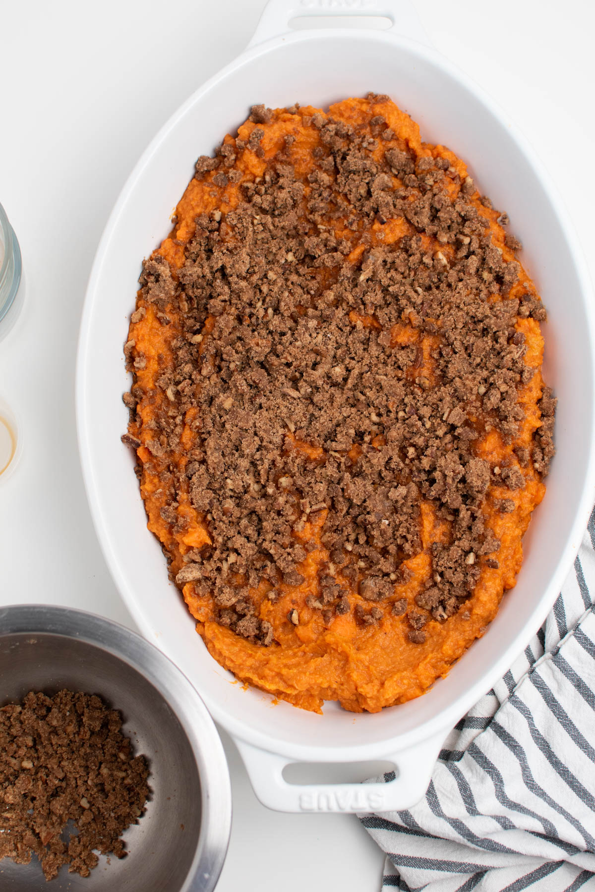 Mashed sweet potatoes in white baking dish with brown sugar topping sprinkled over.