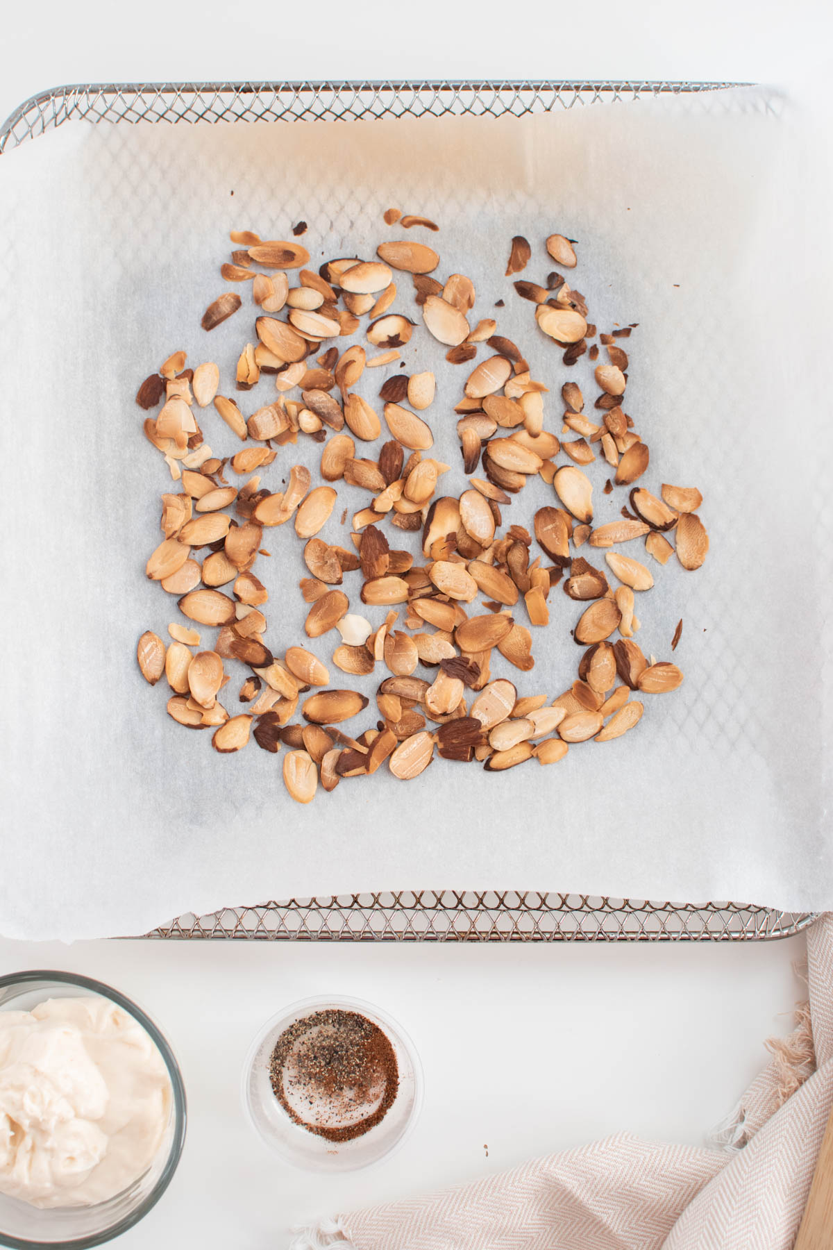 Small roasting pan with several toasted almonds on parchment paper.