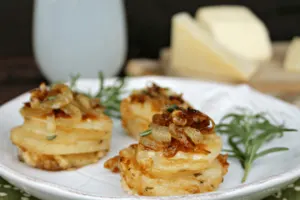 Cheesy Potato and Herb Gratin Stacks Recipe on white plate with green garnish.