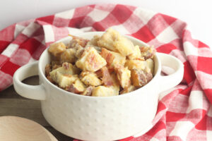 Crock Pot Cheesy Ranch Potatoes in white serving bowl with red and white checkered kitchen towel.