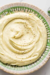 Smooth and creamy parsnip puree garnish with a sprinkle of seasonings in green and white bowl.