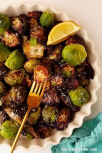 Crispy air fryer roasted brussels sprouts with lemon wedge and gold fork.