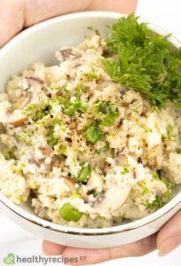 Cauliflower risotto recipe with mushrooms and green garnish in small white bowl.