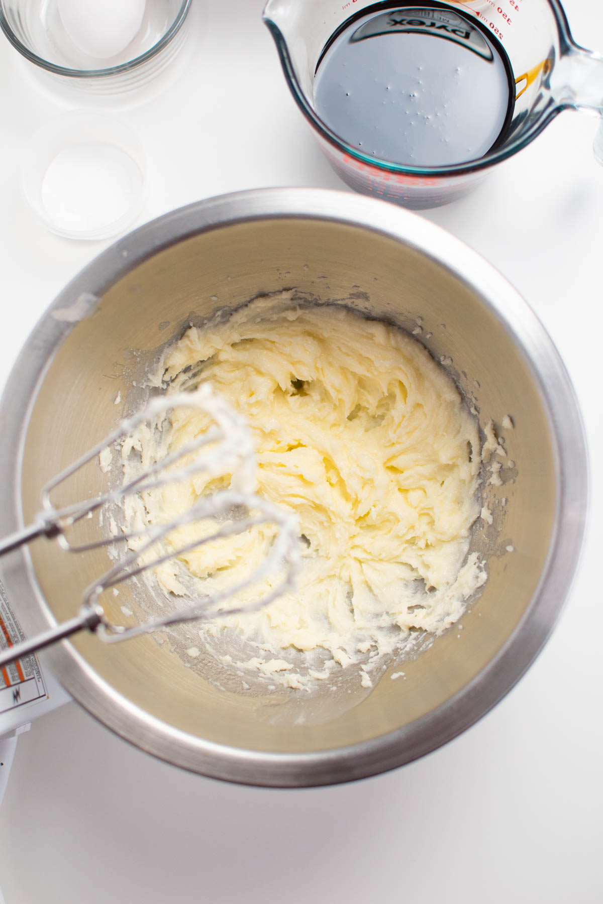 Creamed butter and sugar in metal mixing bowl with electric beaters overhead.