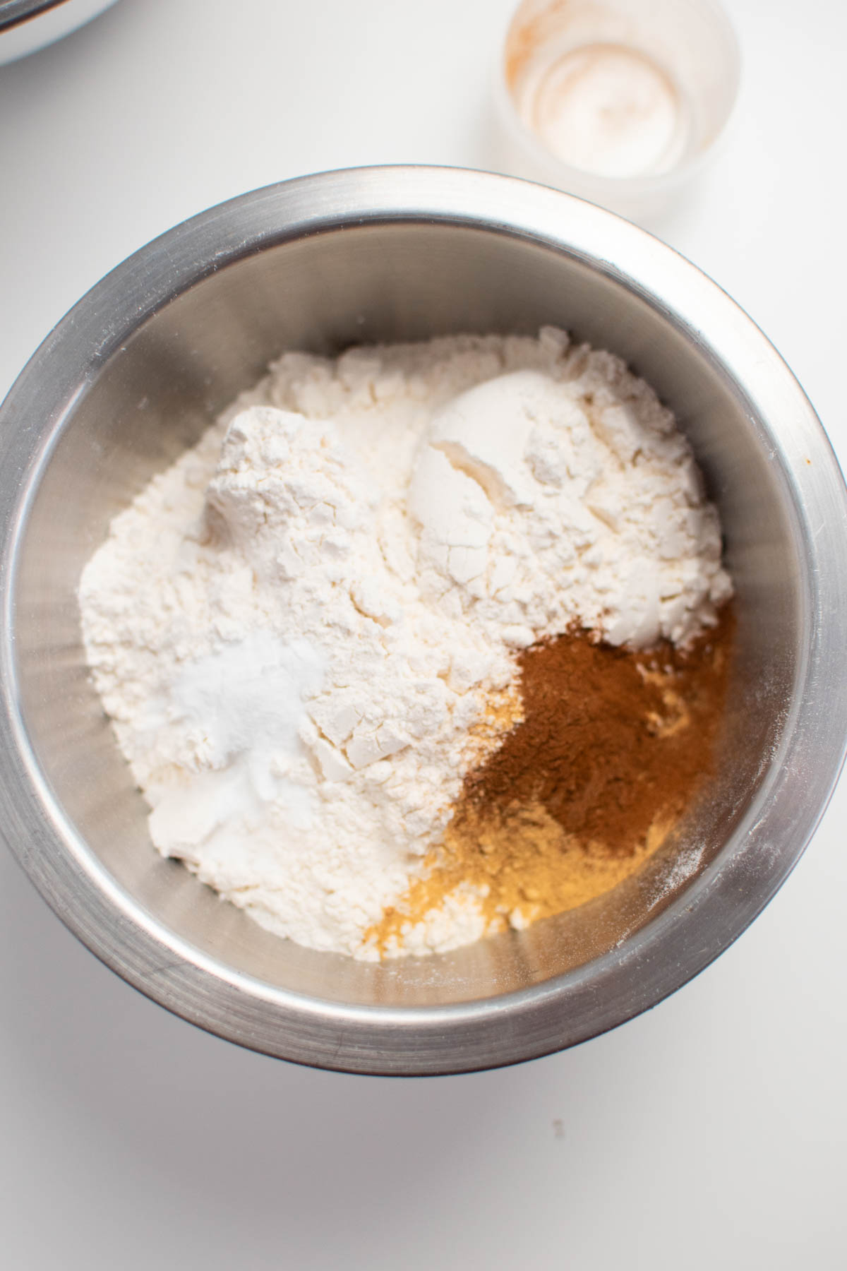 Piles of flour, cinnamon, and ginger in metal mixing bowl.