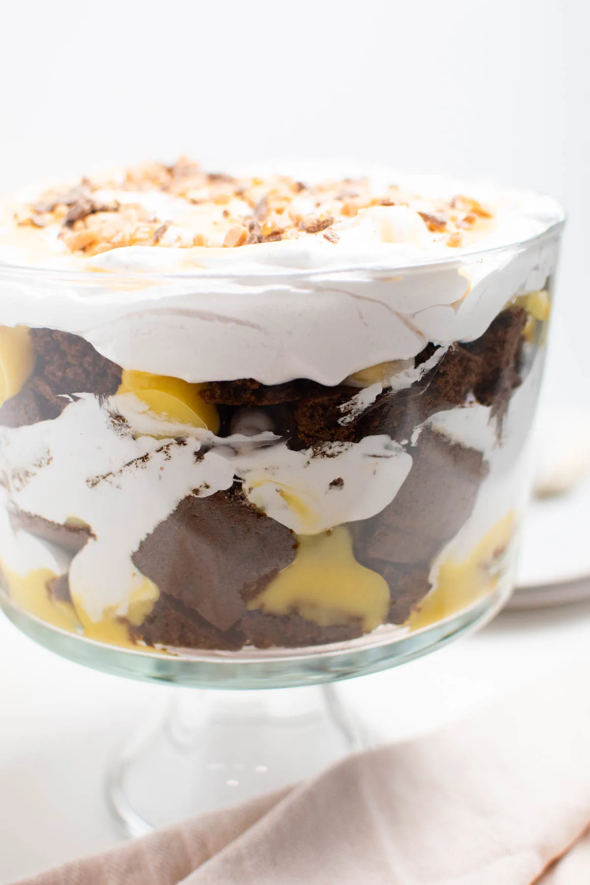 Closeup of gingerbread trifle with whipped cream in glass serving bowl.