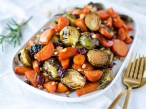 Roasted brussels sprouts and carrots vegetable side dish on white serving platter.