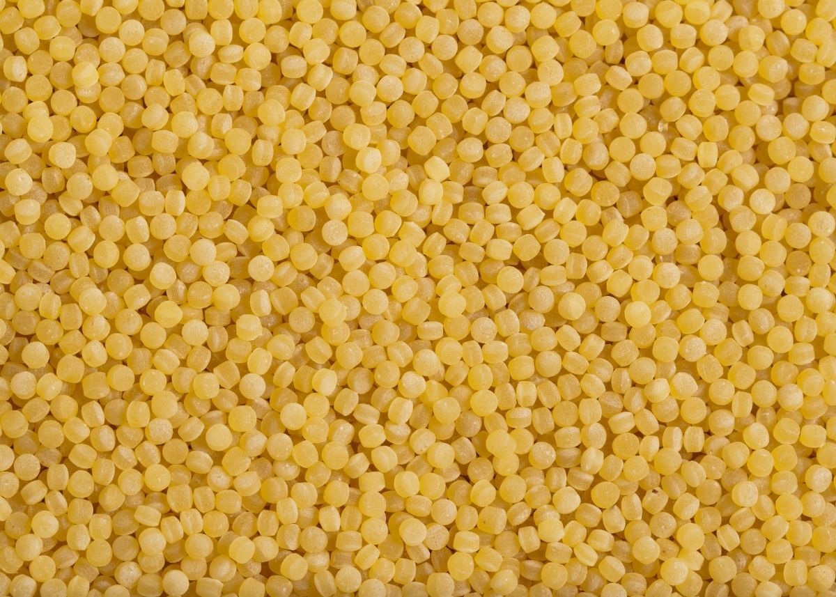 Close up of large pile of yellow colored, uncooked Acini di Pepe pasta.