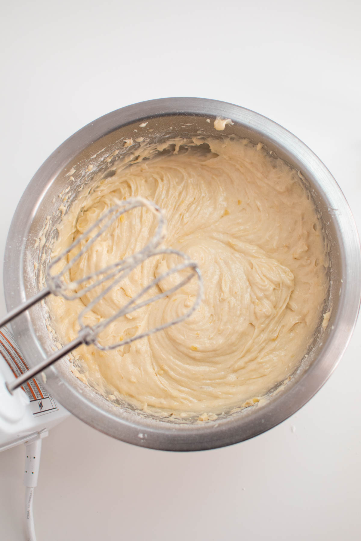Mixed banana bar batter in metal mixing bowl with beaters above.