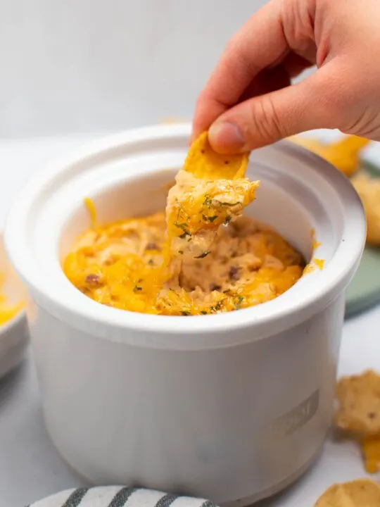Woman hold Frito chip with chili cheese dip spilling off.