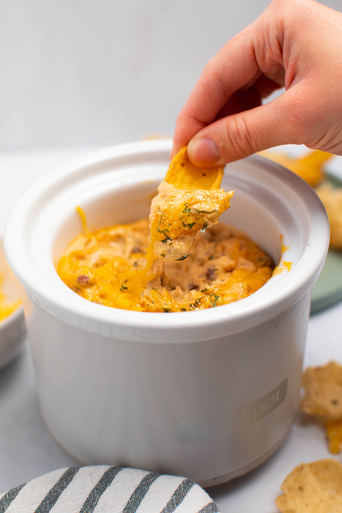 Woman hold Frito chip with chili cheese dip spilling off.