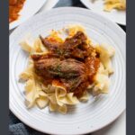 Pinterest graphic with text and photo of white plate with Italian pot roast and egg noodles.
