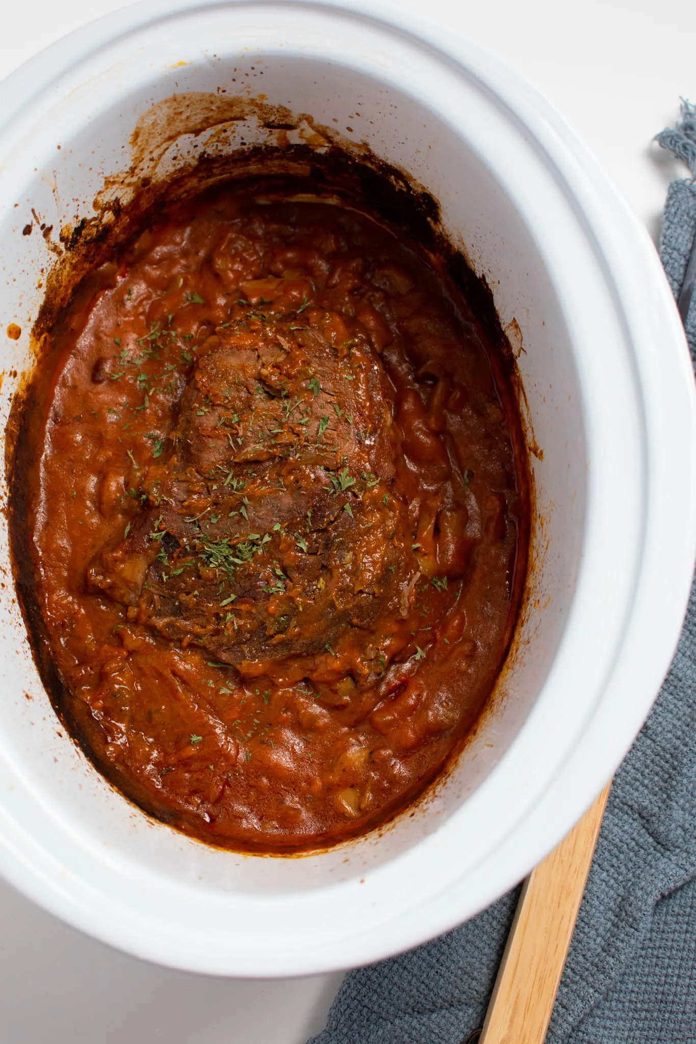 Cooked pot roast and tomato sauce in Crock Pot insert.