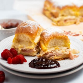 Two Monte Cristo sliders on white plate with fresh raspberries and raspberry jam.