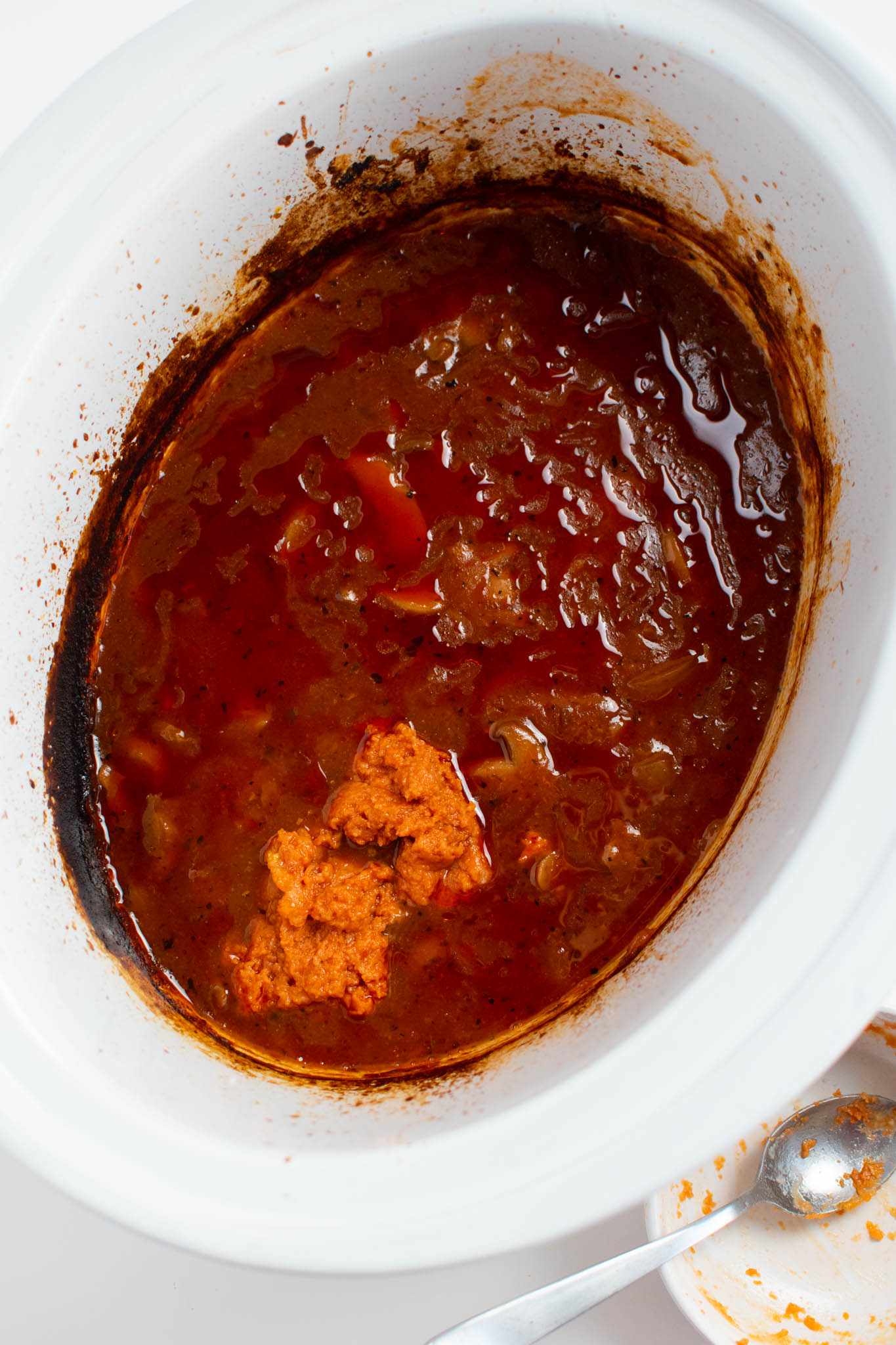 Lump of tomato paste mixture and tomato sauce in Crock Pot.