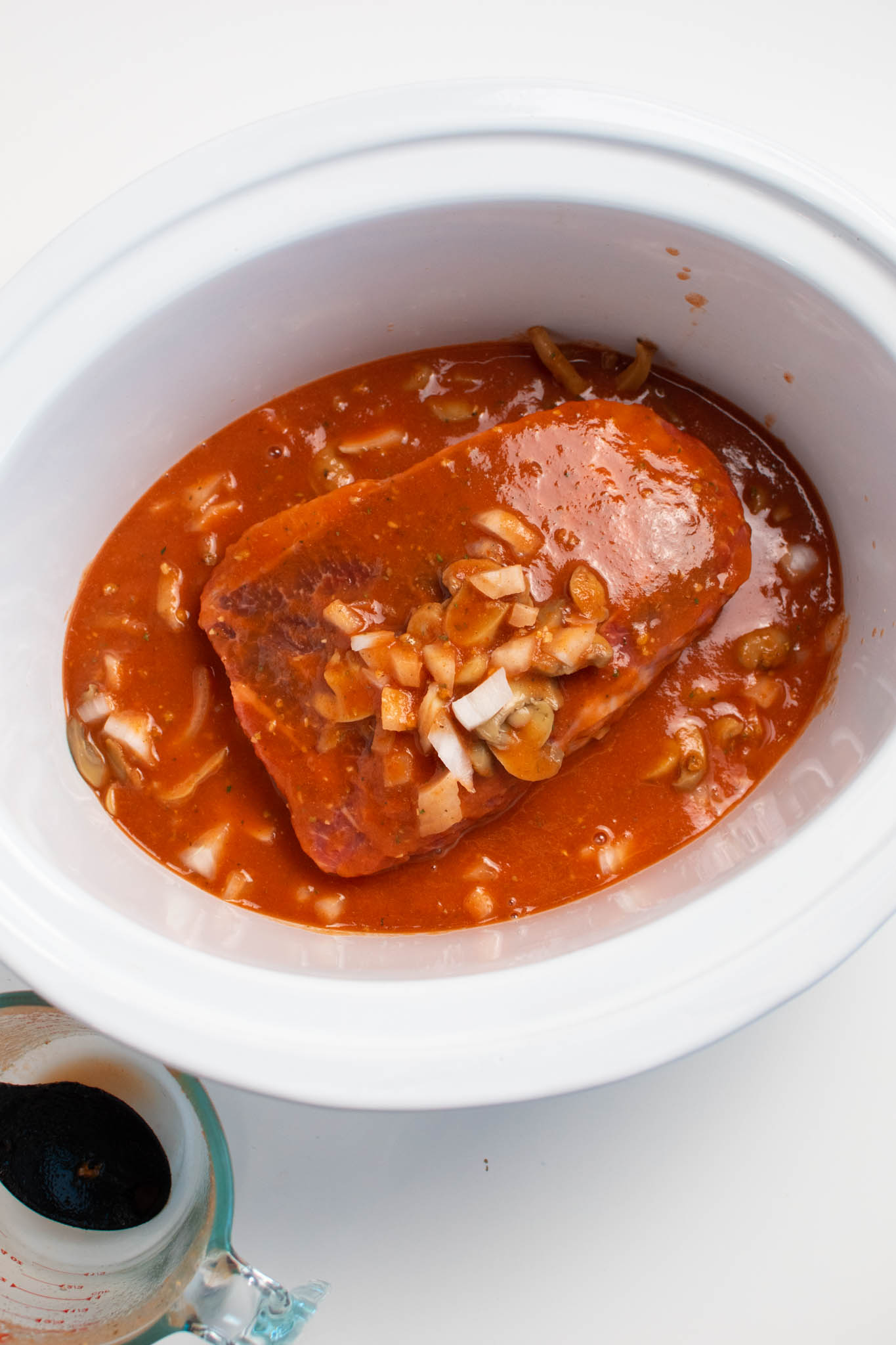 Tomato sauce, onions, and mushrooms on raw roast in Crock Pot.
