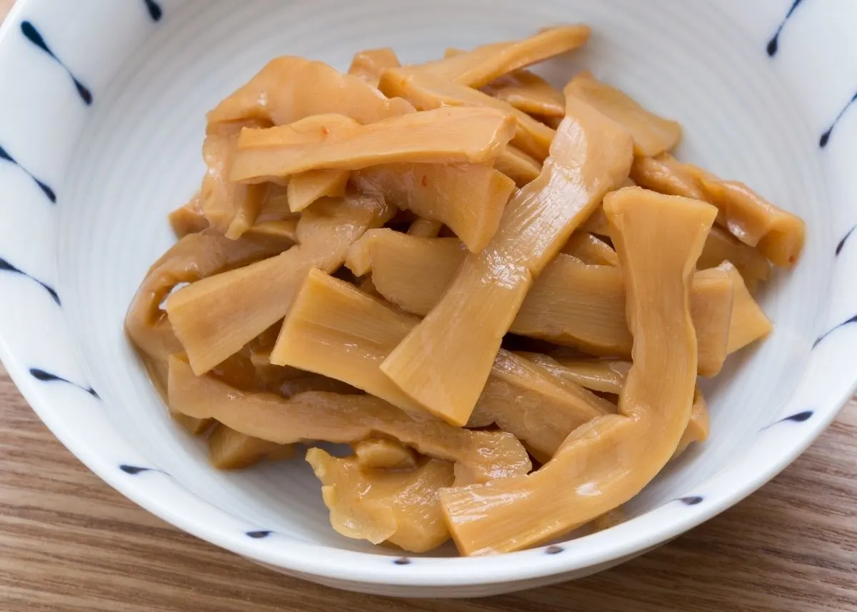 Closeup of several cooked bamboo shoots in a blue and white bowl.