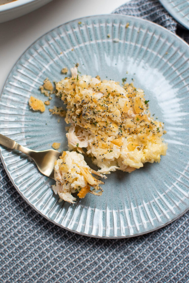 Blue plate with serving of chicken poppy seed casserole on it and fork with some casserole on it.