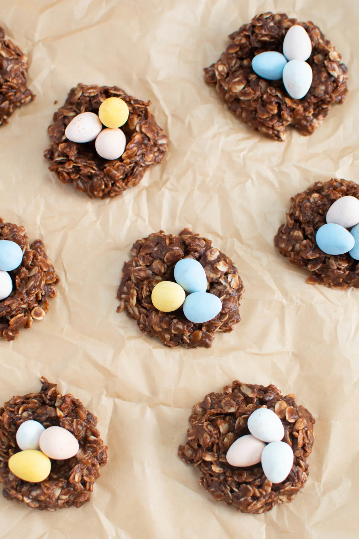 Several no bake nest cookies filled with chocolate eggs on crumpled parchment paper.