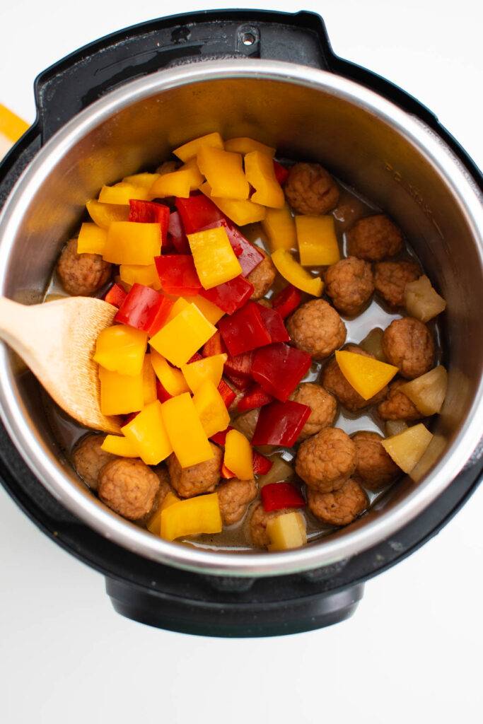 Chopped bell peppers in Instant Pot with sweet and sour meatballs.