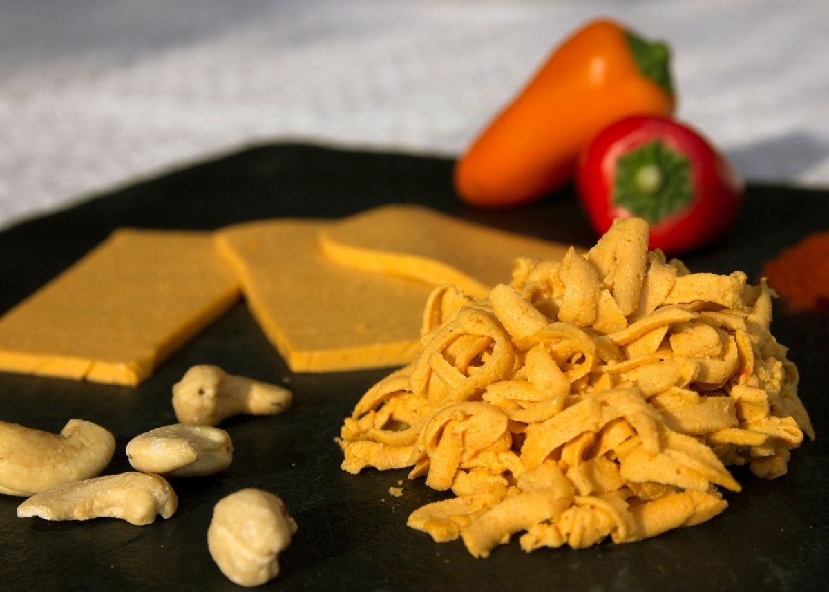 Commercial vegan cheese shreds and slices with cashew nuts and mini peppers.