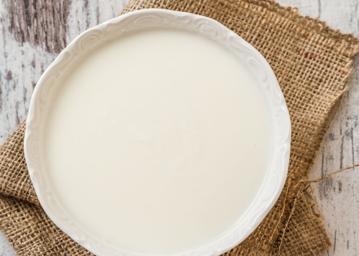 Plain white yogurt in a large white bowl on a burlap cloth.