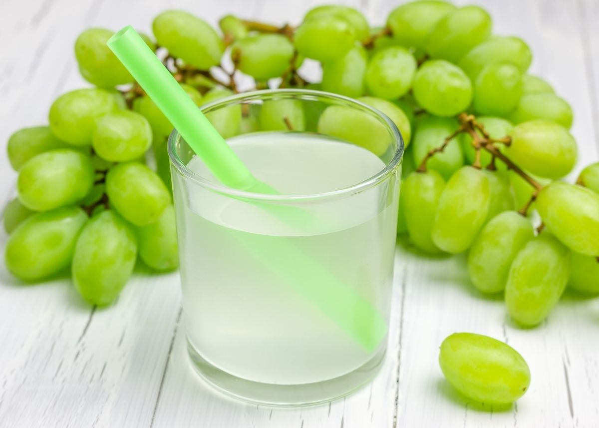 Green grapes on the vine and a glass of white grape juice.