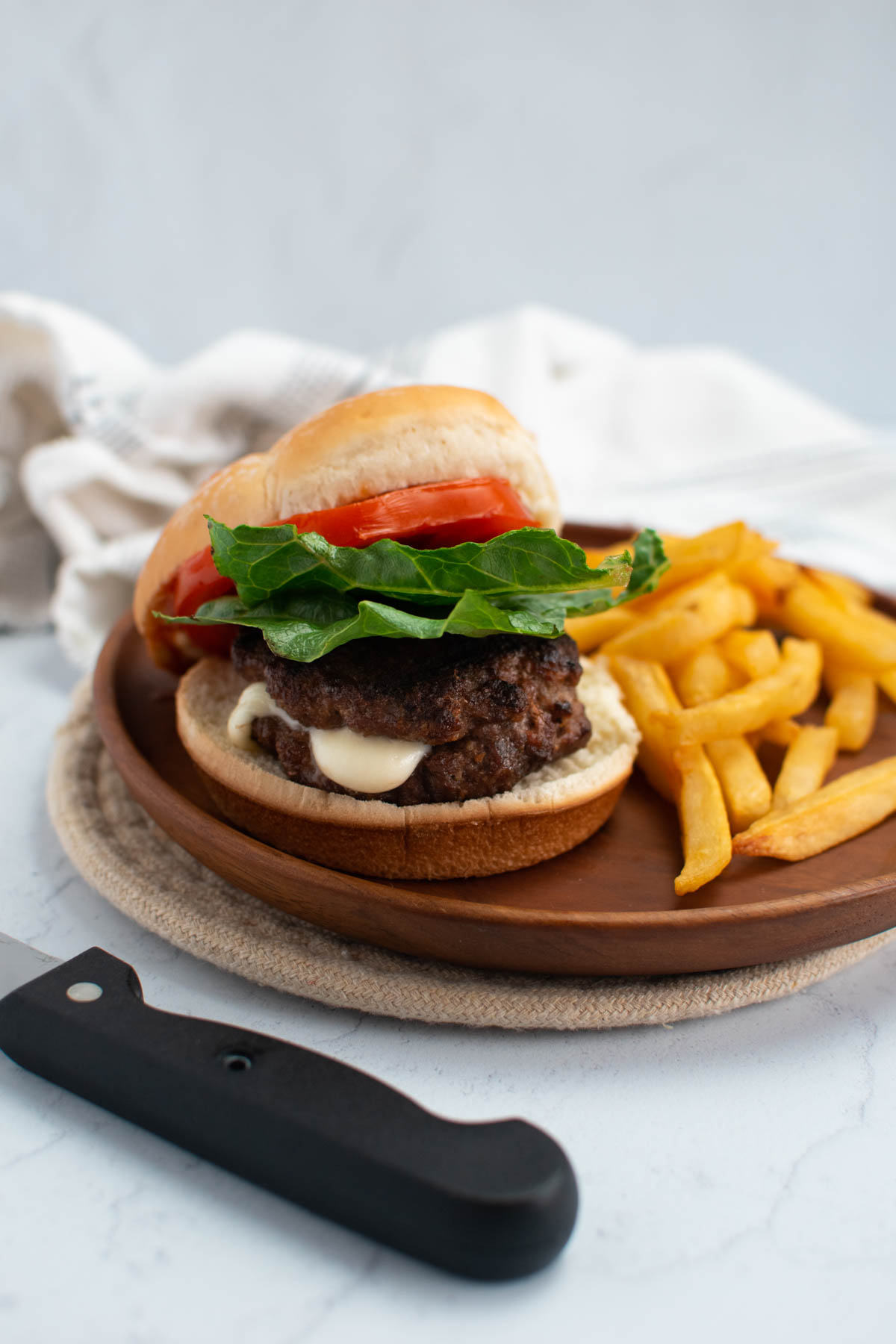 Mozzarella cheese stuffed hamburger on wood plate with french fries.