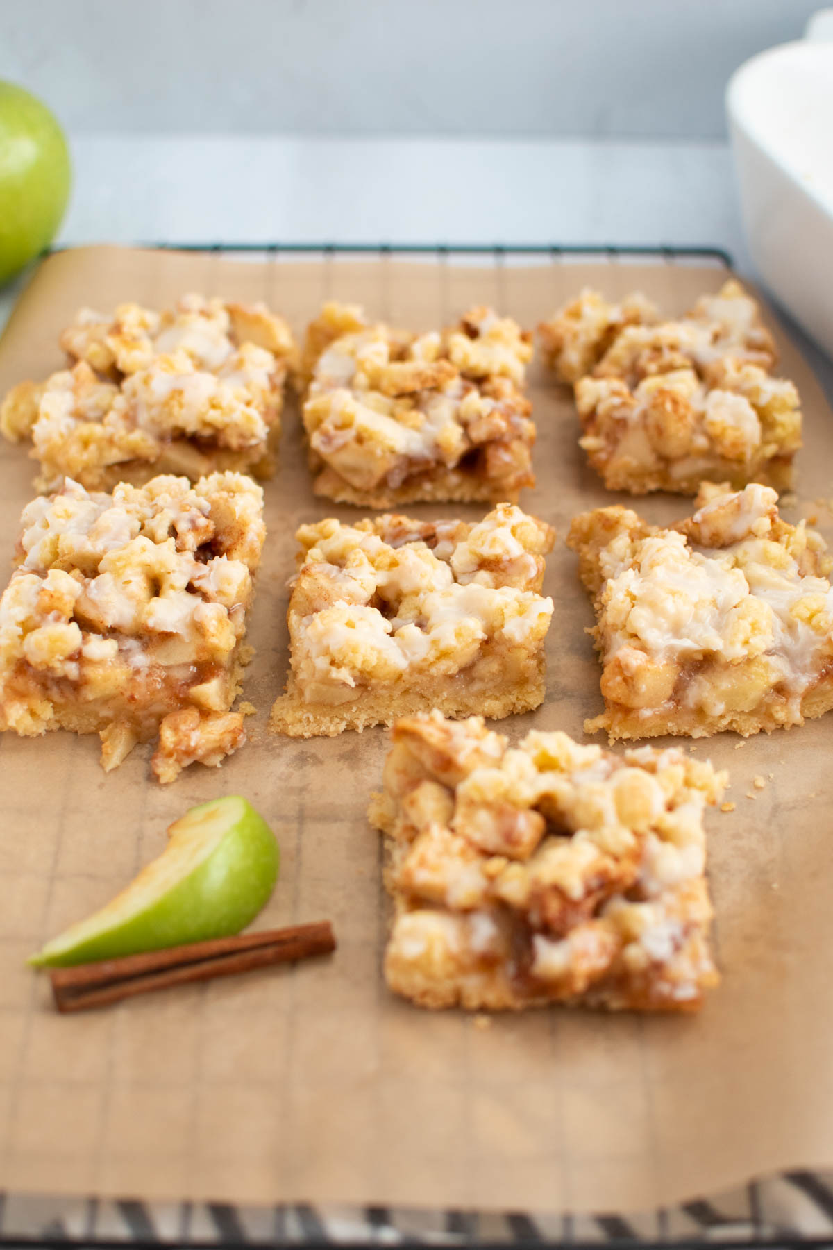 Several apple streusel bars on parchment lined baking sheet.