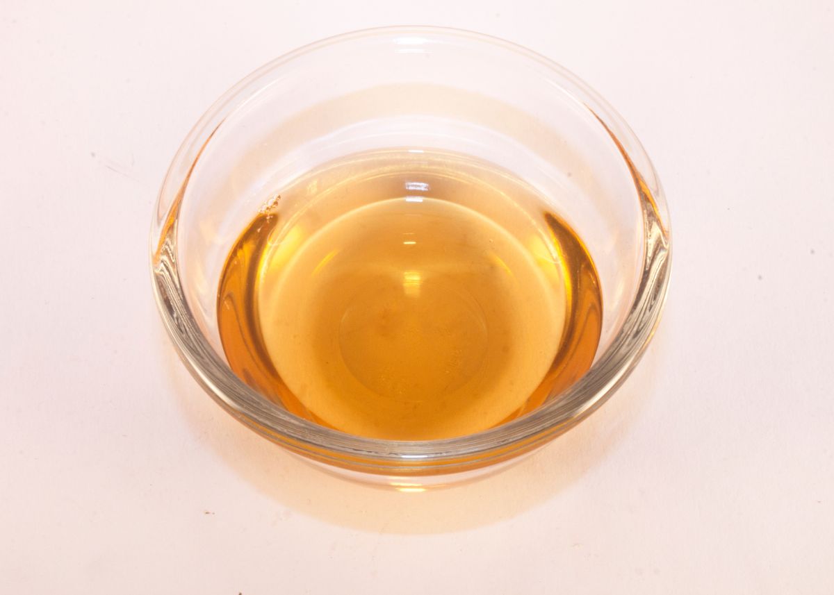 Close up of champagne vinegar in a small clear kitchen prep bowl on white surface.