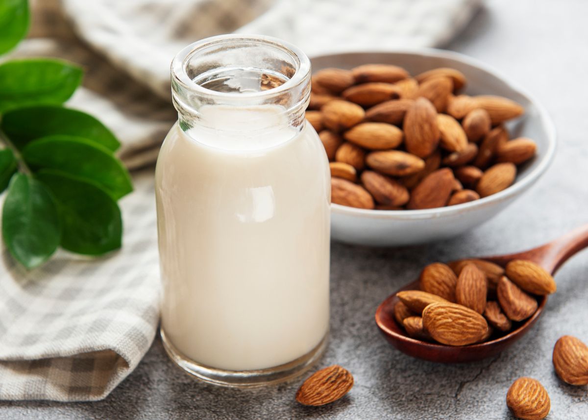 Almond milk in a glass jar next to a bowl of whole almonds.