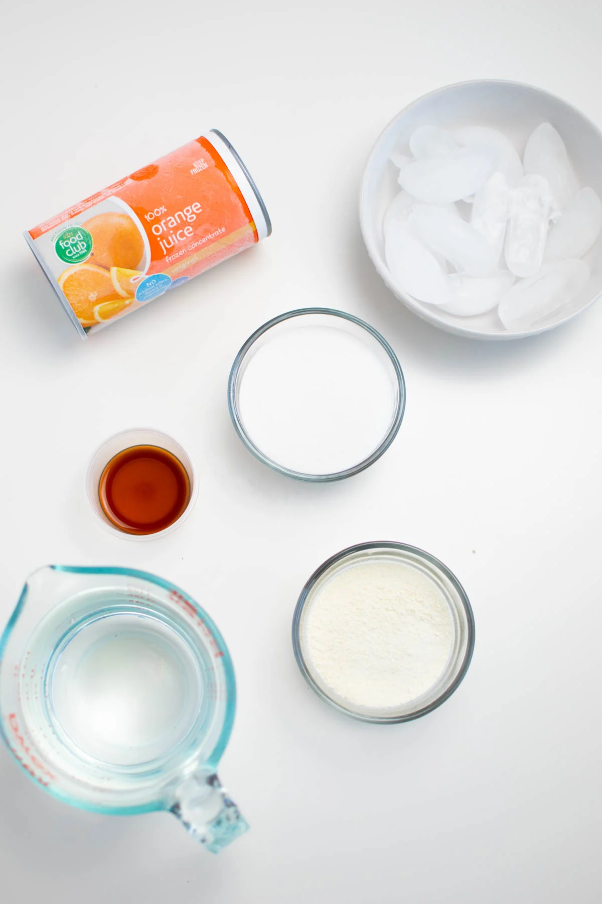 Orange Julius ingredients in bowls including ice cubes, sugar, and milk.