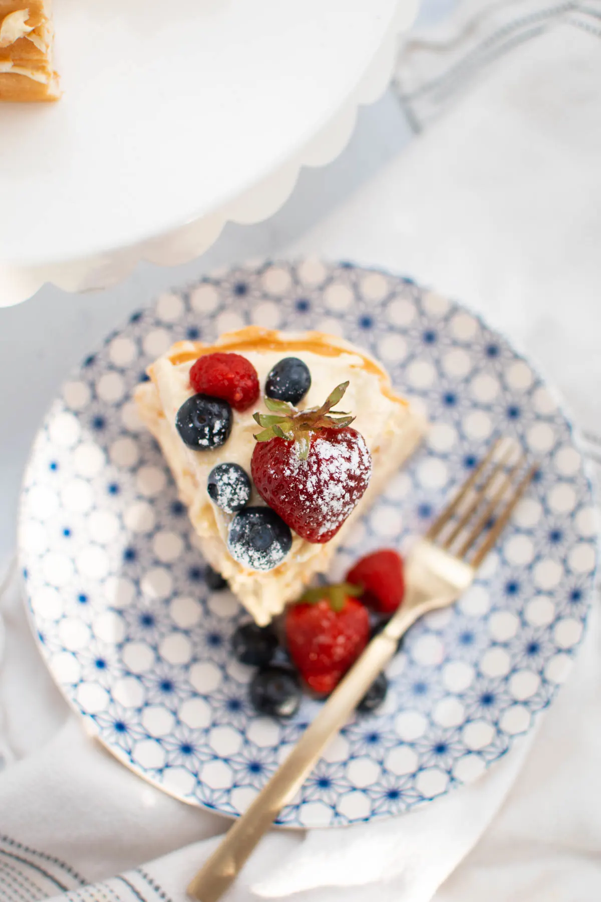 Slice of waffle cake with fresh berries on blue and white plate.