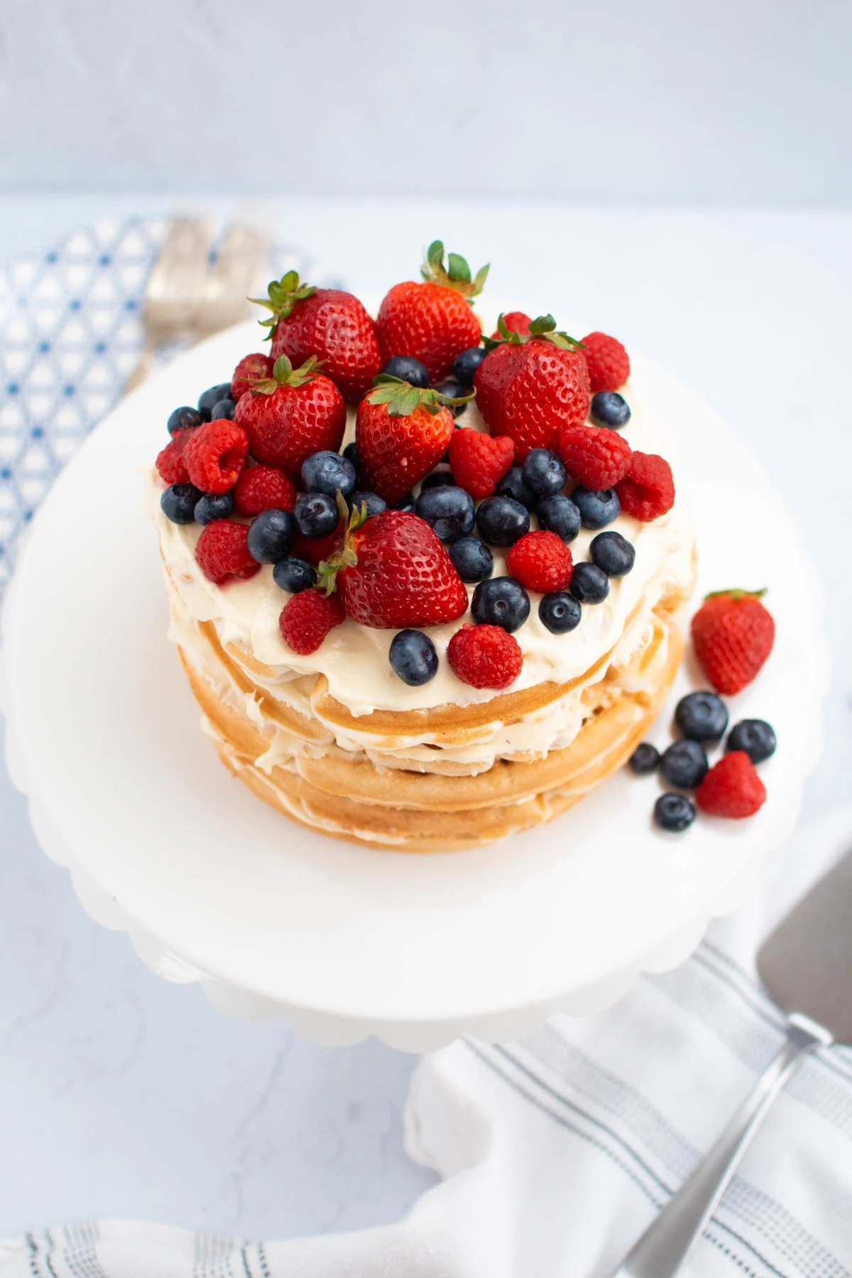 White waffle cake with fresh berries and pudding filling on cake stand.