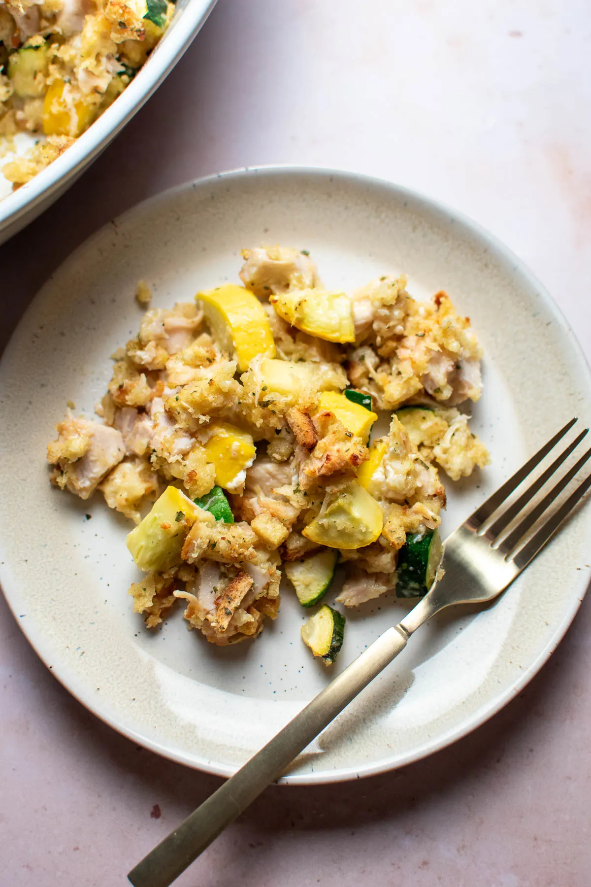 Chicken zucchini casserole and gold fork resting on beige plate.