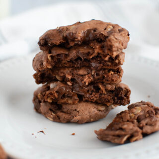 Stack of broken German chocolate cake mix cookies with gooey chocolate chips on white plate.