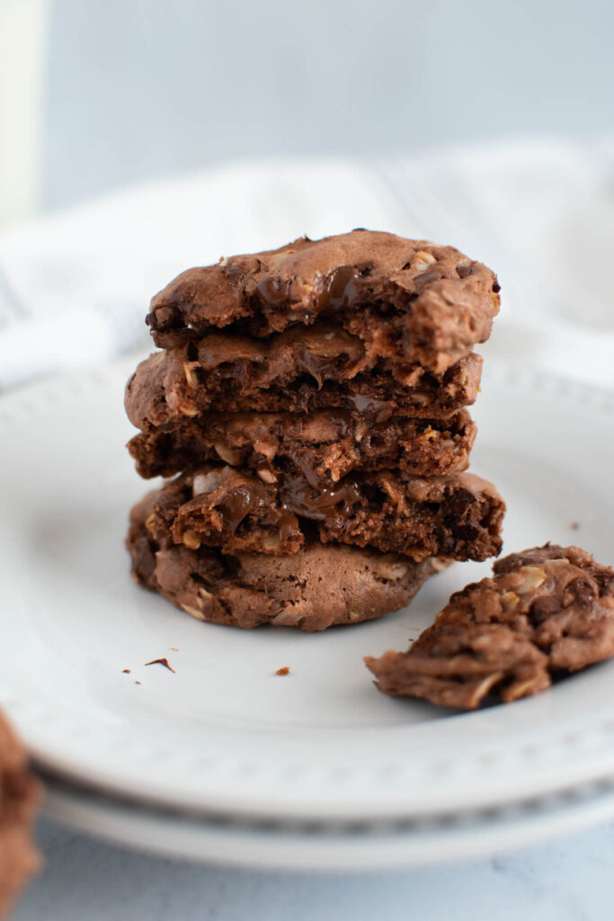 Stack of broken German chocolate cake mix cookies with gooey chocolate chips on white plate.