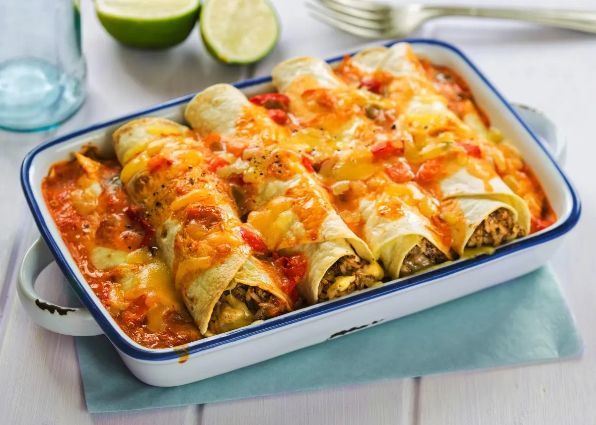 Enchiladas topped with red sauce and cheese in a casserole baking dish.
