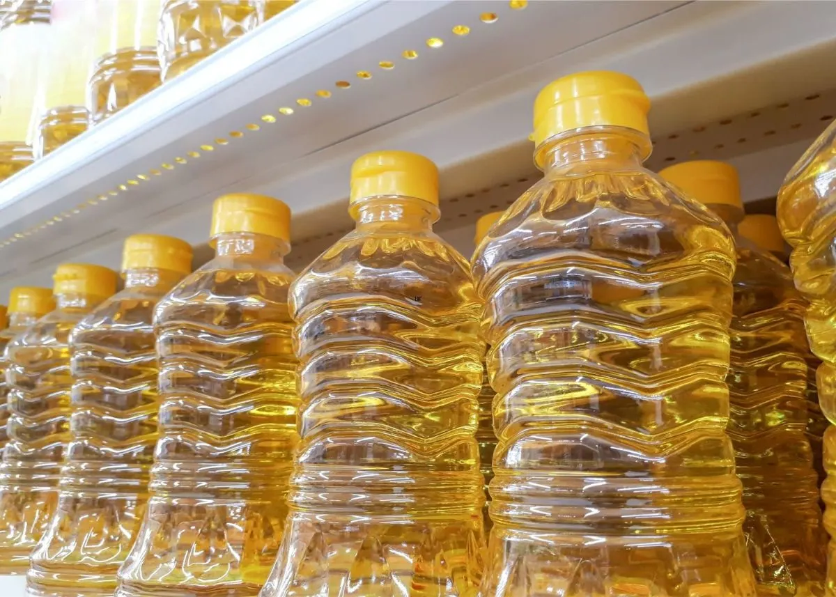 Several bottles of vegetable oil on store shelves with golden yellow caps.