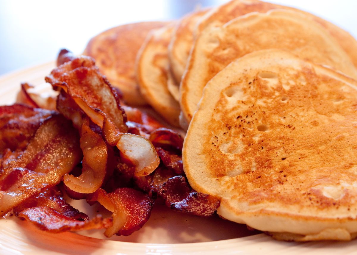 Several fluffy pancakes and a pile of crispy bacon on a platter.