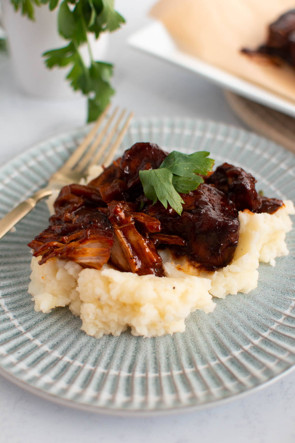 Crock Pot pork ribs with barbeque sauce and mashed potatoes on blue plate.