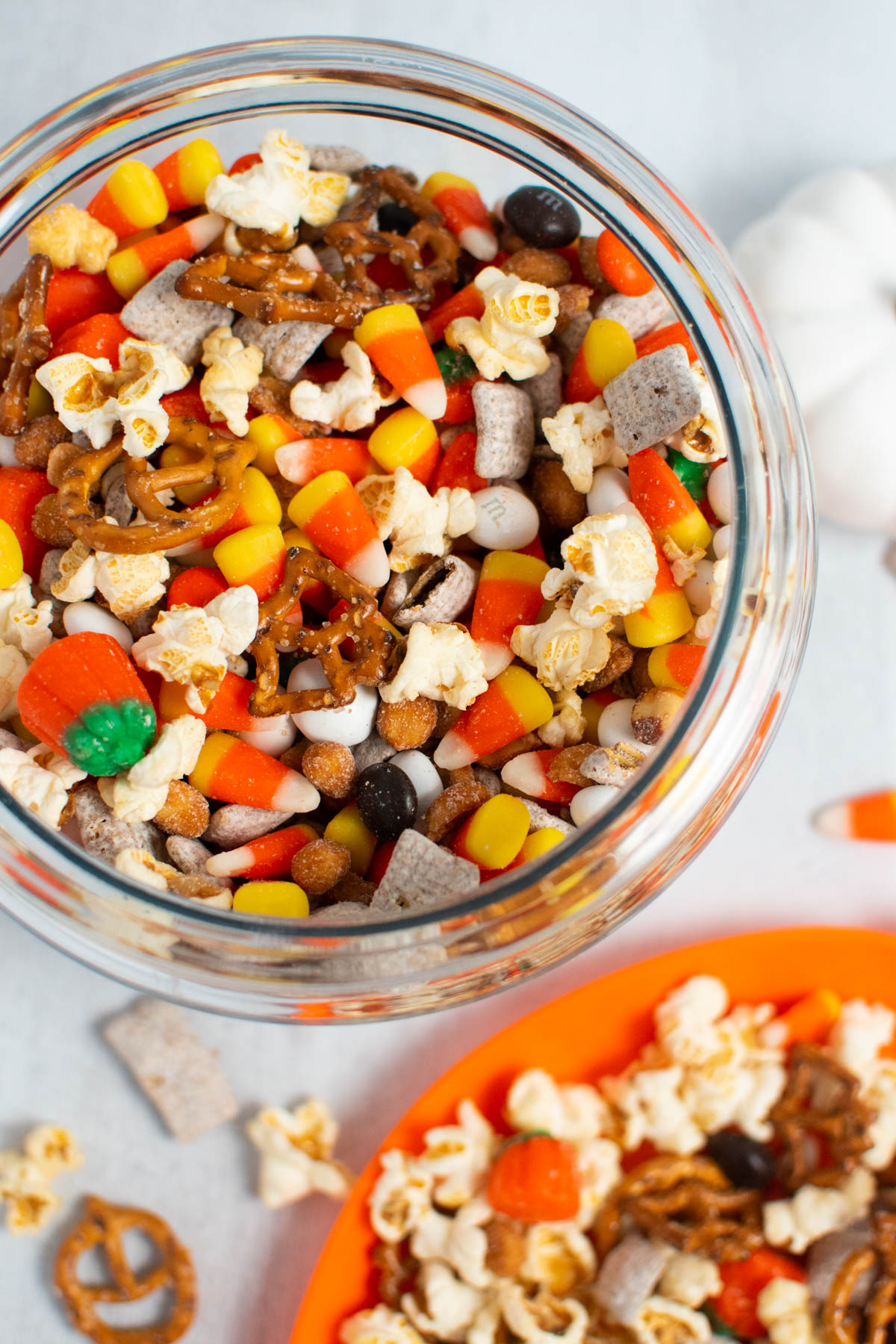 Overhead photo of Halloween popcorn mix with pretzels and candy in glass jar.