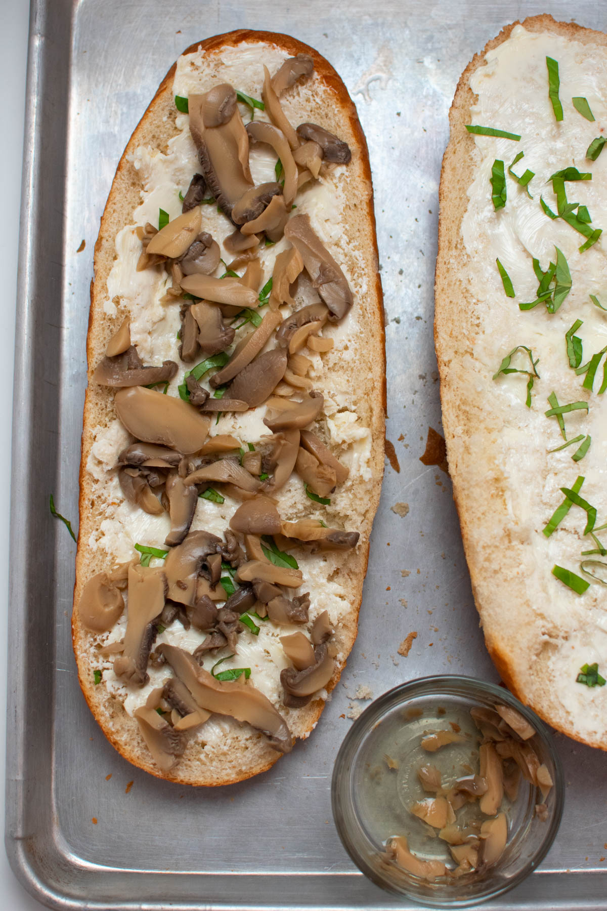 Mushroom pieces on half of French bread all on baking sheet.