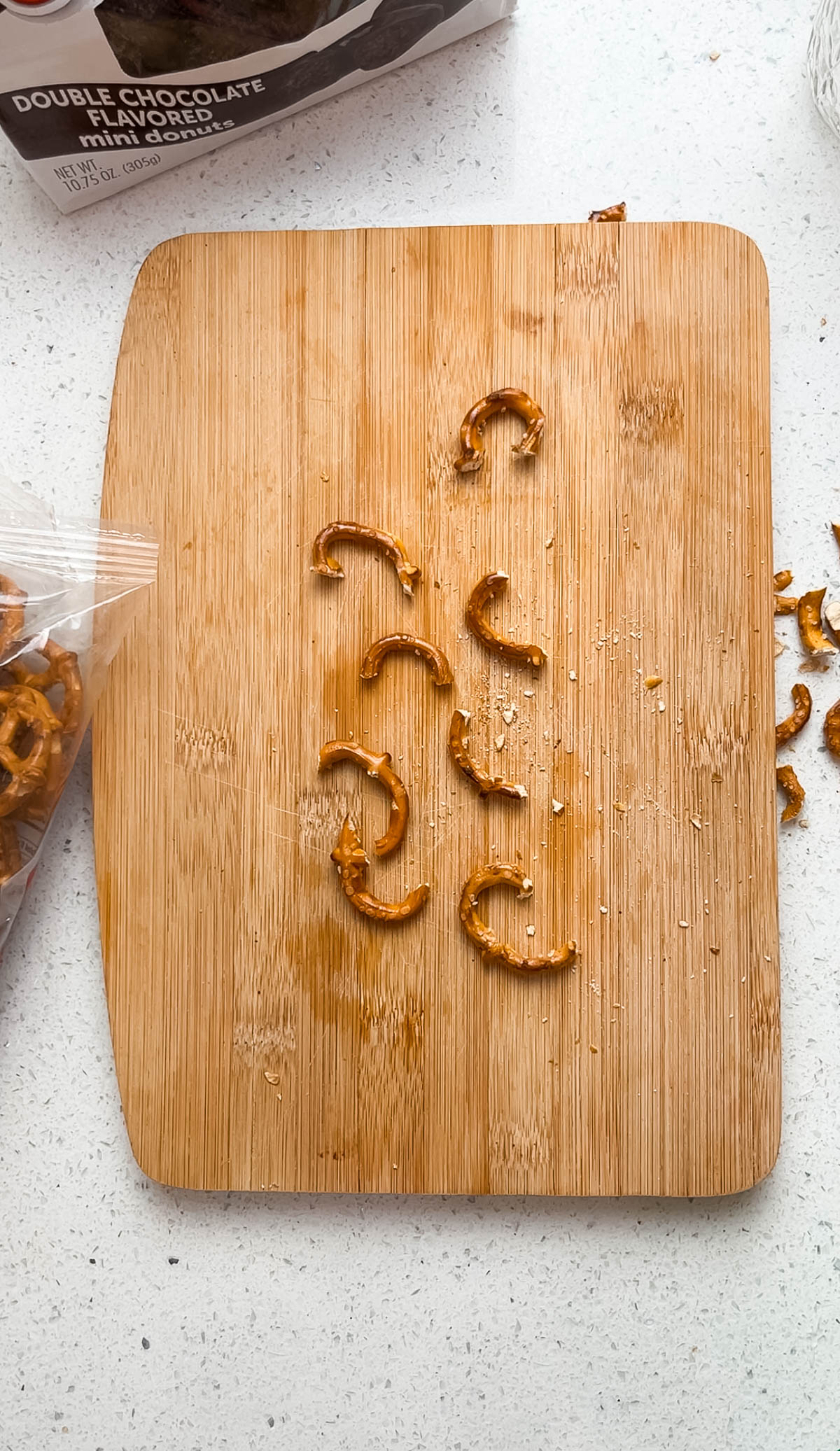 Broken pretzel pieces on wood cutting board.