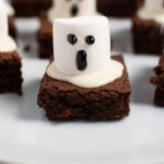 Pinterest graphic with text and photo of ghost brownies with marshmallows on white platter.