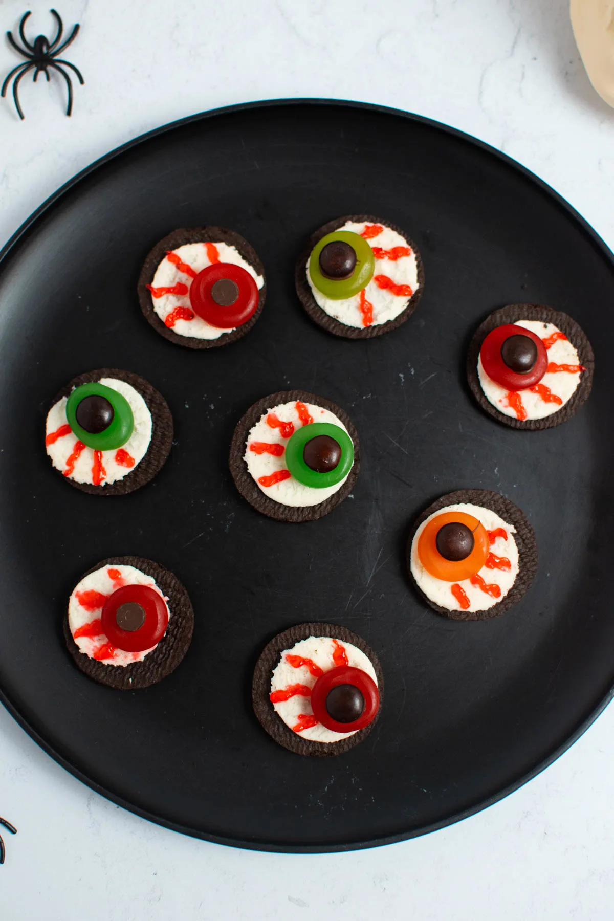 Oreo cookie eyeballs with M&M's on black plate.