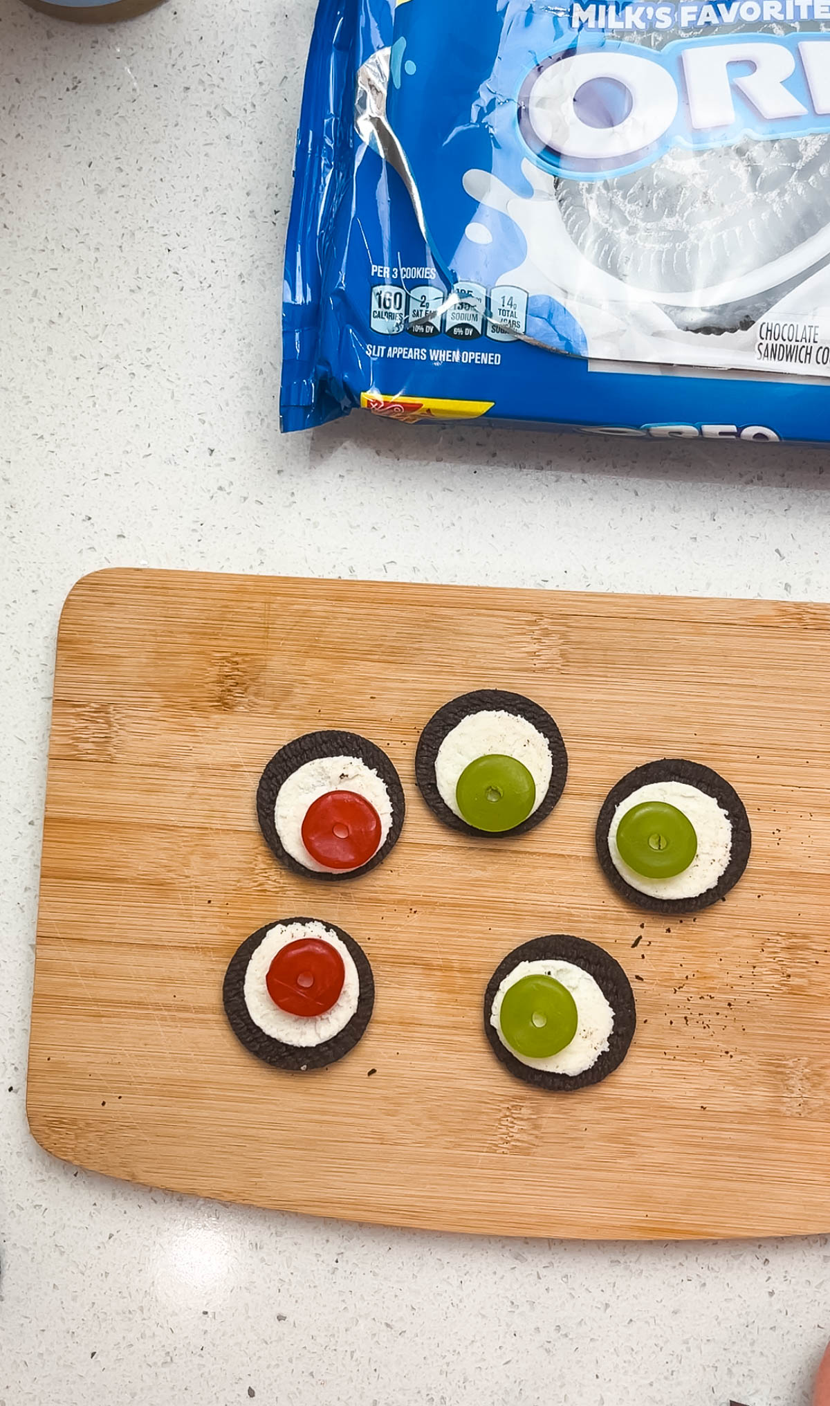 Oreo cookies with frosting showing and Lifesaver gummies on wood cutting board.